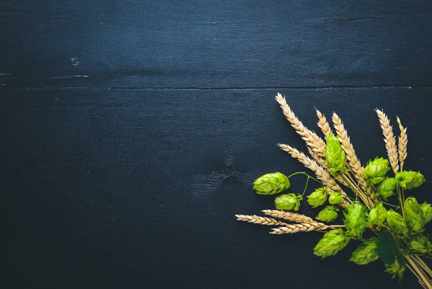 Wheat and hops on a wooden background. Top view. Free space for text. - Foto, imagen