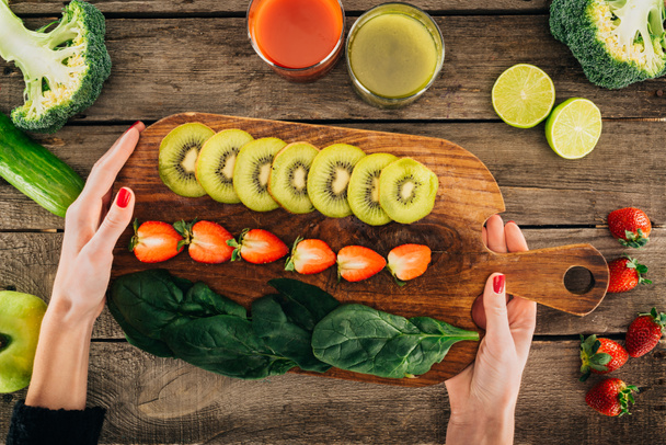 woman and cutting board with fresh vegetables and fruits - Foto, afbeelding