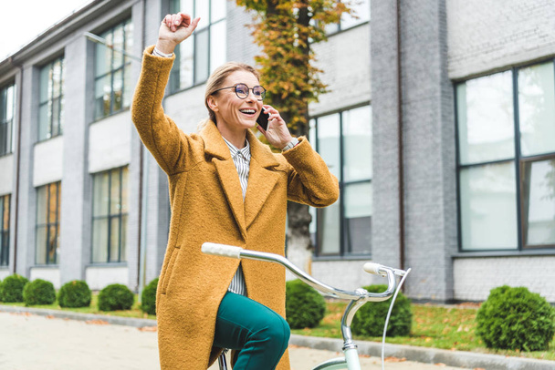 woman talking on smartphone while riding bicycle - Photo, Image