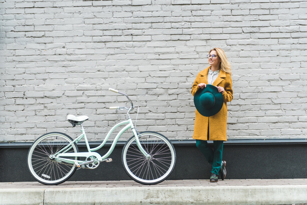 woman at wall with bicycle - Photo, Image