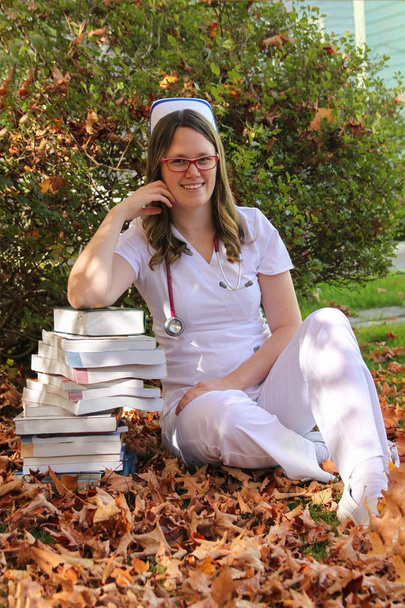 Νέοι νοσοκόμα με καπάκι και βιβλία σε εξωτερικούς χώρους - Φωτογραφία, εικόνα