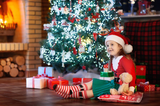 Niño en el árbol de Navidad. Niño en la chimenea en Navidad
  - Foto, Imagen