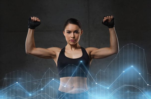 young woman flexing muscles in gym - Foto, Imagen