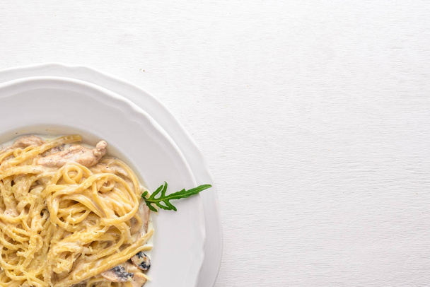 Pasta with chicken and mushrooms. Italian cuisine. On a wooden background. Top view. Free space for text. - 写真・画像