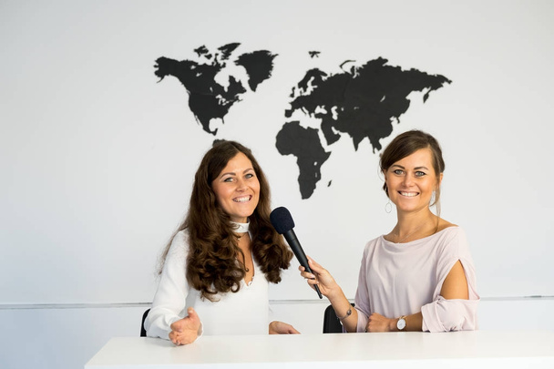 Две девочки-репортёры-близнецы ведут репортаж из белой студии
 - Фото, изображение