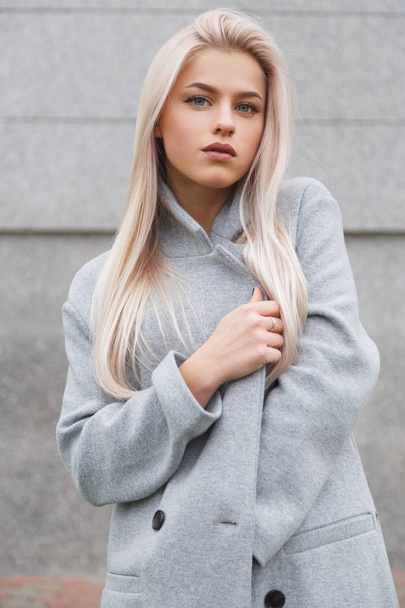 Muotokuva kaunis nuori blondhair nainen harmaa takki. Street muoti näyttää
 - Valokuva, kuva