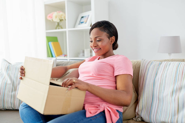happy pregnant woman opening parcel box at home - Фото, изображение
