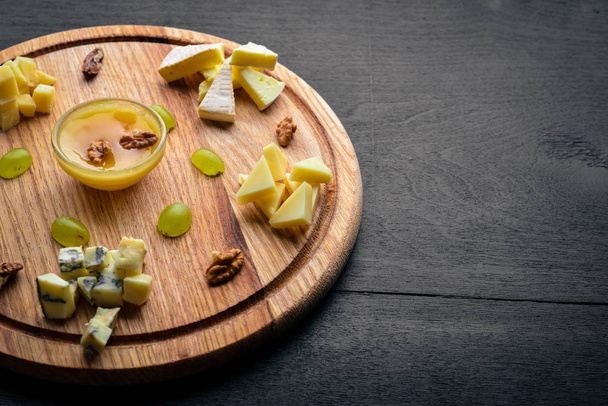 Assorted cheeses, gorgonzola, brie, feta, with honey. On a wooden background. Top view. Free space. - Photo, Image