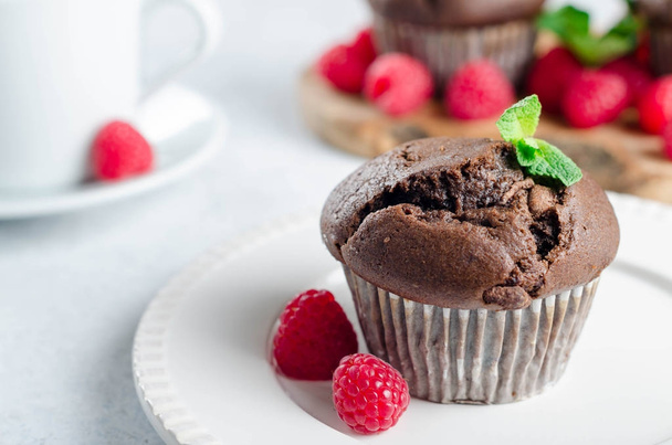 One chocolate muffin on a foreground and two muffins on a wooden - Foto, afbeelding