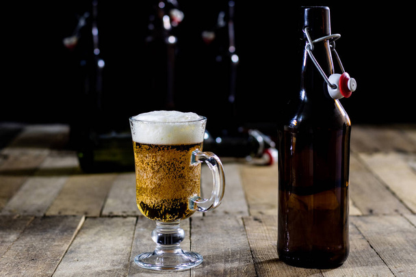 A pint of tasty beer on a wooden table. Beer in pint and beer bo - Fotó, kép