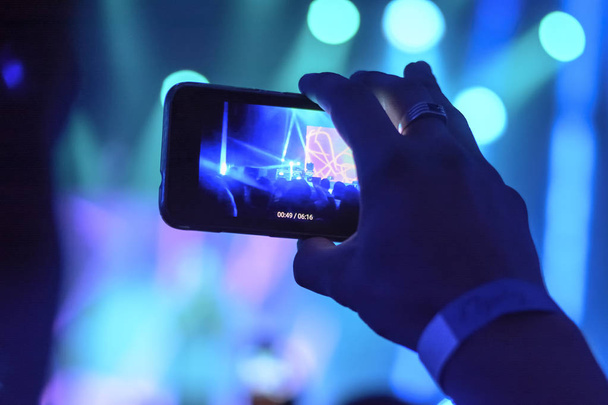 silhouet van handen met een smartphone tijdens een concert - Foto, afbeelding