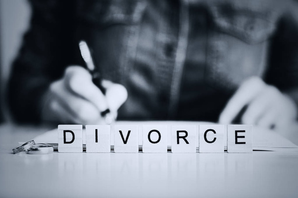Nő megy keresztül válás és aláírása papírok az előtérben a word - válás. tónusú - Fotó, kép