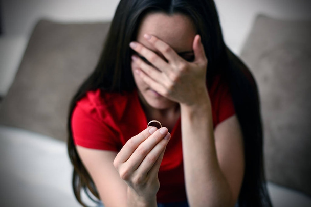 Crying sad young woman with engagement ring in hand close up. Depression after a divorce. Selective focus. - Photo, Image