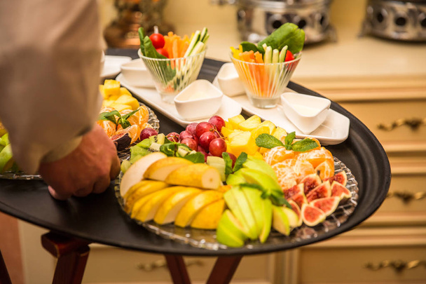 Σερβιτόρος που μεταφέρουν δίσκος με πλάκες με φρούτα και λαχανικά σε κάποια εορταστική εκδήλωση - Φωτογραφία, εικόνα