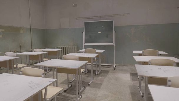 Пустой класс с деревянными столами, белыми и зелеными досками в школе. пустой класс. Заброшенный школьный класс со школьными столами и доской
 - Фото, изображение