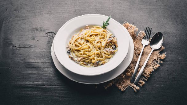 Pasta with chicken and mushrooms. Italian cuisine. On a wooden background. Top view. Free space for text. - Foto, afbeelding