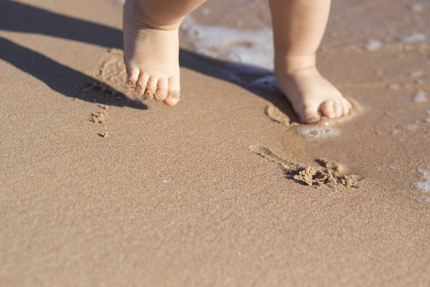 Benen van kinderen staan op het strand. Baby voetjes in het zand. Zomer strand achtergrond. Zomer vakantie concept. Kopiëren van ruimte. - Foto, afbeelding