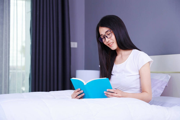 woman reading a book on bed in bedroom at home - Foto, Bild
