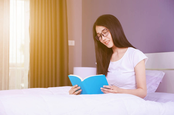 woman reading a book on bed in bedroom at home - Foto, imagen
