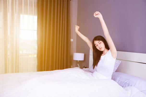 Frau wacht auf und legt Hand auf Bett im Schlafzimmer - Foto, Bild