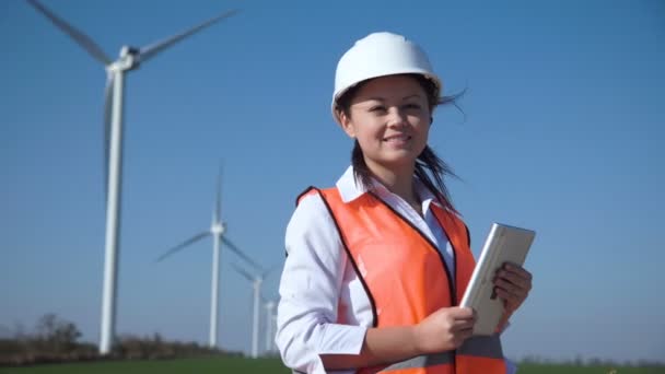 Улыбающаяся женщина-инженер, стоящая против ветровой электростанции
 - Кадры, видео