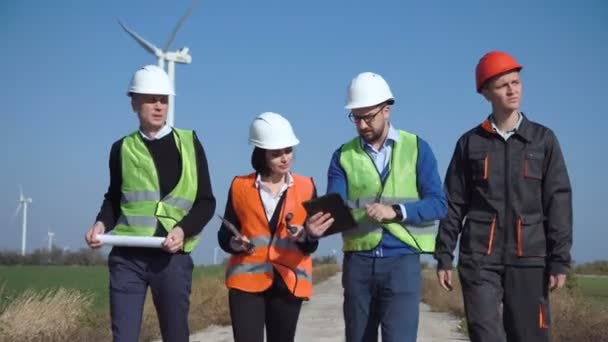 Ingenieros caminando por carretera contra turbinas eólicas
 - Metraje, vídeo