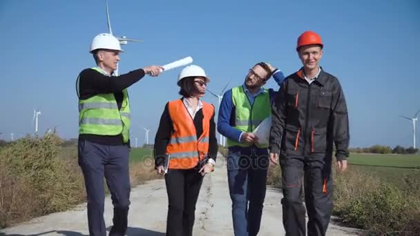 Ingenieros caminando por carretera contra turbinas eólicas
 - Imágenes, Vídeo