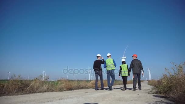 Skupina inženýrů chůzi proti větrné farmy - Záběry, video