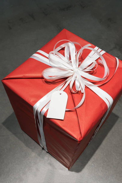 Червона обгорнута подарункова коробка з білою вишуканою краваткою та порожнім вітанням
 - Фото, зображення
