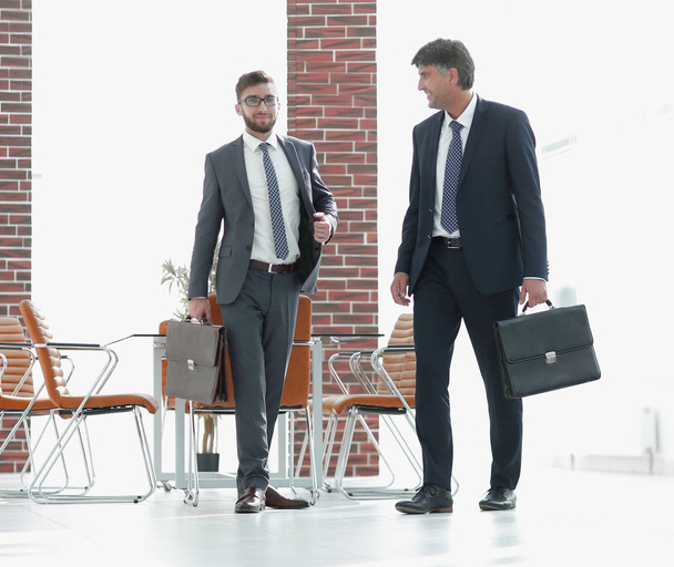 Two businessmen walking along in modern office building - Fotó, kép