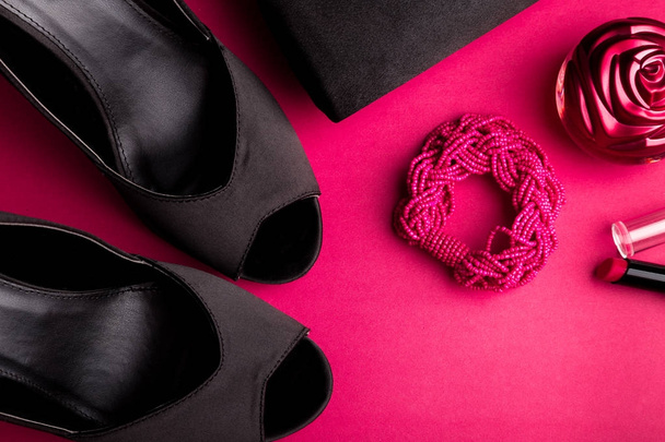 Fashion Lady Accessoires Set. Noir et rose. Minimal. Chaussures noires, bracelet, parfum, rouge à lèvres et sac sur fond rose. Pose plate
. - Photo, image