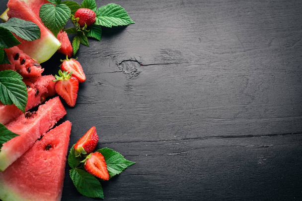 Watermelon, strawberries, mint. On a wooden board. Fruit Slicing. Top view. Free space for your text. - Foto, Bild