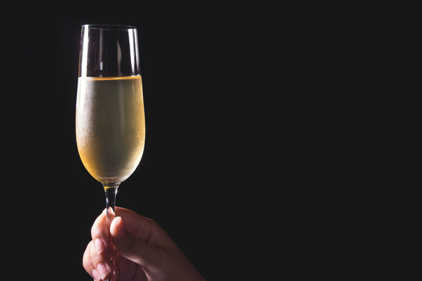 Mulher mão segurando copos de champanhe no fundo preto
 - Foto, Imagem