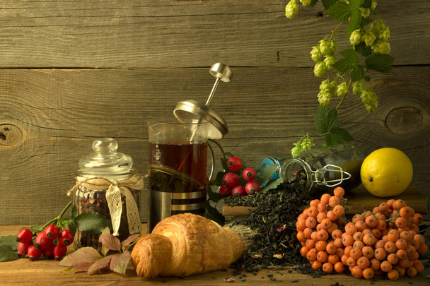 Hot tea jug on a wooden background surrounded by autumn fruits - Photo, Image
