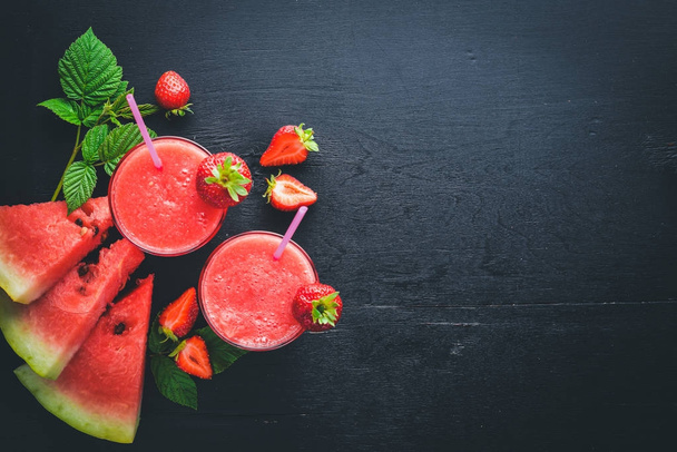Fresh cocktail of watermelon and strawberries. Mint, ice. On a wooden board. Top view. Free space for your text. - 写真・画像