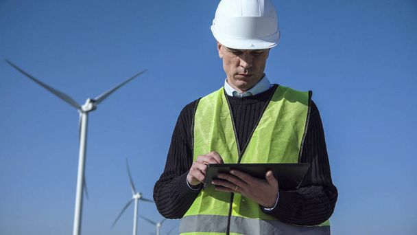 Ingegnere che utilizza tablet digitale contro turbina eolica
 - Foto, immagini