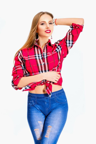 Mladá sexy žena oblečená v džínách a kostkovanou košili pózuje ve studiu - Fotografie, Obrázek
