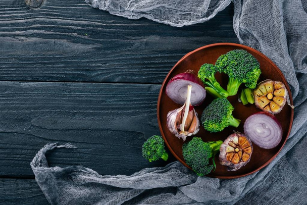 Fresh vegetables on a clay plate. On a wooden background. Top view. Free space for your text. - Foto, afbeelding