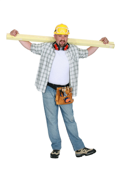 A carpenter holding a plank. - Foto, Bild