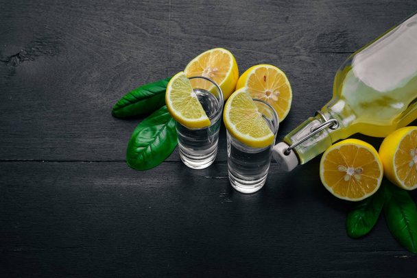 Tequila, fresh lemon and lemon juice. On a wooden background. Top view. Free space for your text. - Φωτογραφία, εικόνα