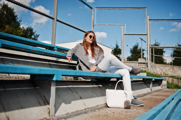 Girl in gray coat with sunglasses at small street stadium. - Foto, Imagen