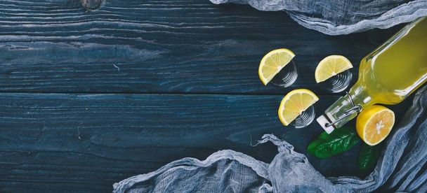 Tequila, fresh lemon and lemon juice. On a wooden background. Top view. Free space for your text. - 写真・画像