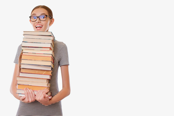 girl holding heavy stack of books - Foto, afbeelding