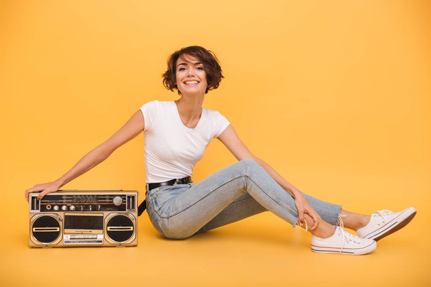Portrait of a pretty joyful girl sitting with record player - Photo, Image