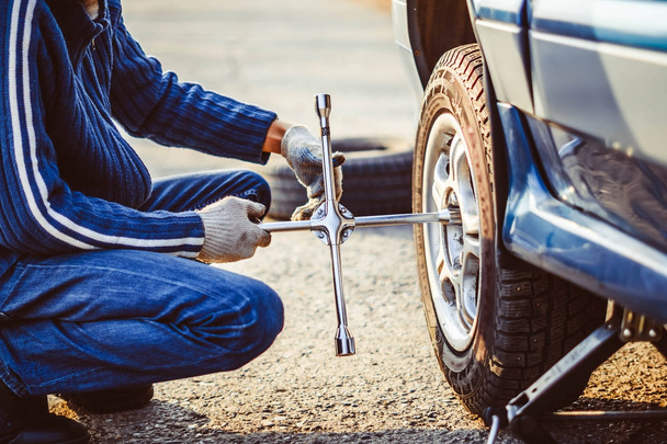 Человек меняет колесо на машине
 - Фото, изображение