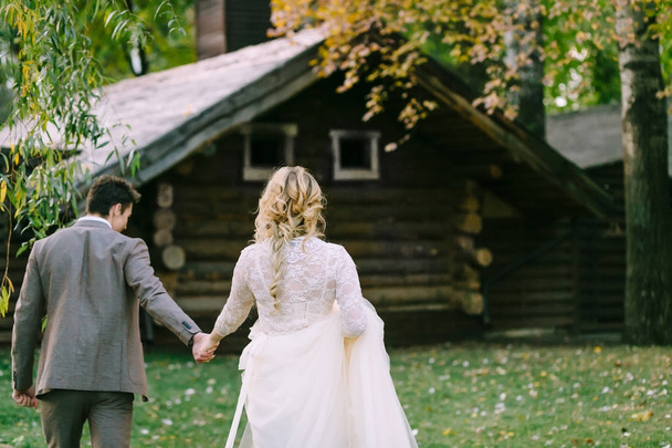 Bride and groom go to wooden home in the forest. Autumn wedding. Artwork - Foto, imagen
