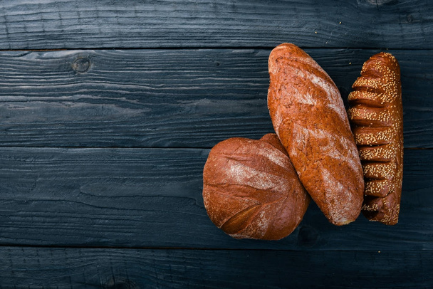 Assortment of bread and baking. On a wooden background. Top view. Free space for your text. - Foto, Imagem