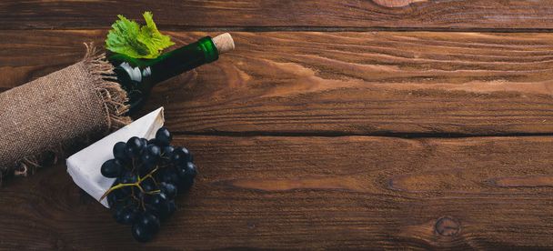 A bottle of wine and grapes. On a wooden background. Top view. Free space for your text. - Foto, immagini