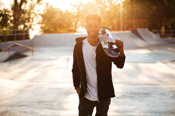 Smiling male teenager guy holding skateboard - Foto, Imagen