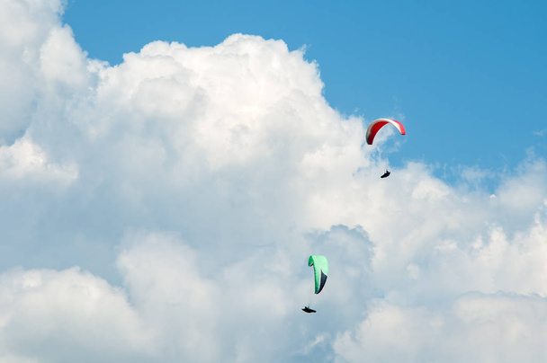 zwei Gleitschirme fliegen in den blauen Himmel vor dem Hintergrund der Wolken.  - Foto, Bild